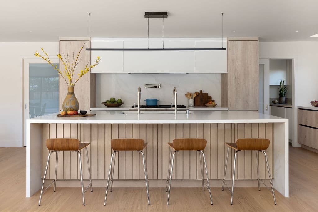 Luxury kitchen remodel by Barcci Builders — modern island with wood paneling and marble countertops
